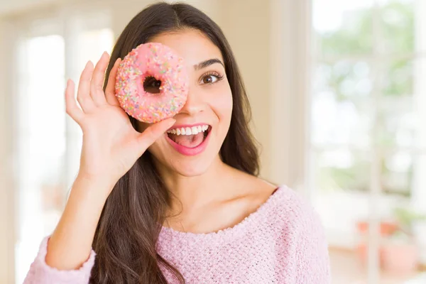 Belle jeune femme souriante regardant à travers beignet rose sur le — Photo