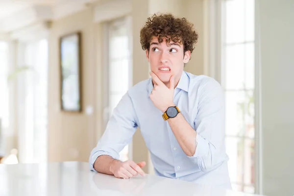 Young business man with curly read head Thinking worried about a question, concerned and nervous with hand on chin