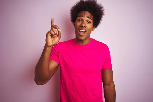 アフロヘアの若いアメリカ人男性は 孤立したピンクの背景の上に立って 成功したアイデアで指を指さすTシャツを着ています 終了し ナンバーワン — ストック写真