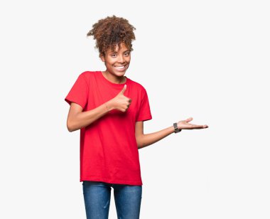 İzole arka plan gösteren palm el ve yukarıya, mutlu ve neşeli gülümseyen baş parmakları Tamam jest yapıyor güzel genç Afro-Amerikan kadın