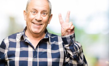 Mutlu yüz zafer işareti yaparken kameraya göz kırpıyor ile gülümseyen rahat gömlek giymiş yakışıklı komuta sizde. İki numaralı.