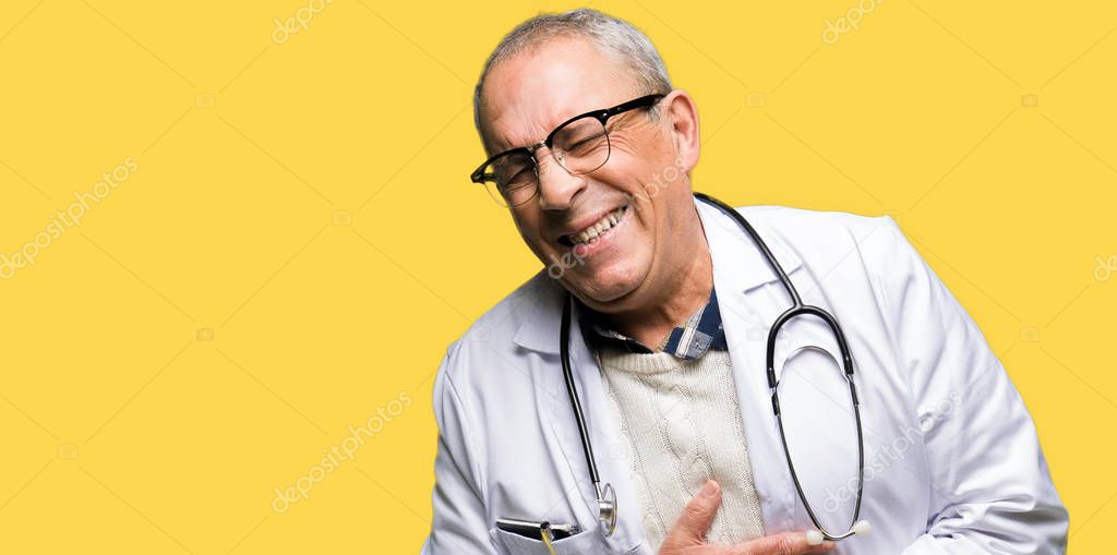 Handsome senior doctor man wearing medical coat Smiling and laughing hard out loud because funny crazy joke. Happy expression.