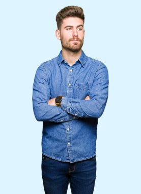 Genç yakışıklı sarışın adam görünümlü yan ve dik dik bakma uzağa düşünce gülümseyen rahat kot gömlek giymiş.