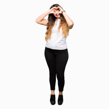 Rahat beyaz t-shirt giyen genç güzel kadın el ve parmaklar işareti ile görünümlü gülümseyen kalp şekli yapıyor