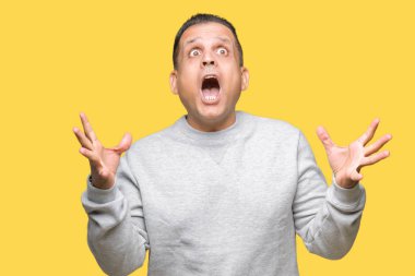 Üzerinde spor kazak giyen orta yaş Arap adam deli kutluyor arka plan izole ve başarı için kaldırdı kollarını açarak hayrete ve heyecanlı çığlık gözleri açık. Kazanan kavramı