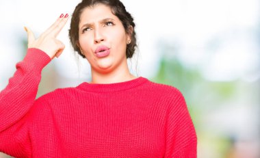 Kırmızı kazak ve çörek giyen genç güzel kadın çekim ve kendini el ve parmak işaret öldürme baş için intihar jest.