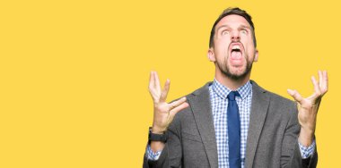 Yakışıklı iş adamı giyen takım elbise ve kravat deli ve deli çığlık ve saldırgan ifade ve silah ile bağırdı kaldırdı. Hayal kırıklığı kavramı.