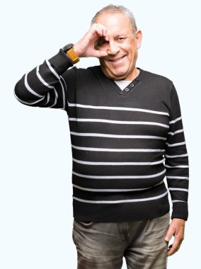 El gülümseyen, göz mutlu yüz ile parmaklarla görünümlü ok jest yapıyor kış çizgili kazak giyen yakışıklı kıdemli adam.