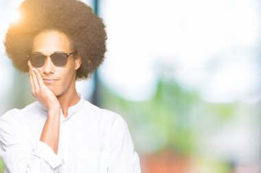 Düşünme seyir yorgun ve sıkılmış depresyon sorunları ile güneş gözlüğü takıyor afro saçlı genç Afro-Amerikan adam silah geçti.