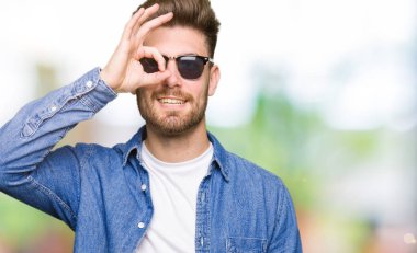 Gülümseyen, parmakları ile mutlu yüz üzerinden seyir göz el ile ok jest yapıyor Kot ceket giyen genç yakışıklı zarif adam.