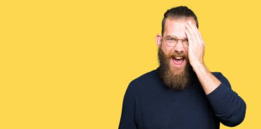 Gözlük ve yüz ve sürpriz duygu kendinden emin gülümseme ile el ile bir göz kapsayan boğazlı kazak giyen genç sarışın adam.