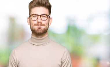 Komik surat ile yanakları şişirme gözlüklü genç yakışıklı iş adamı. Ağız ile hava, deli ifade şişirilmiş.