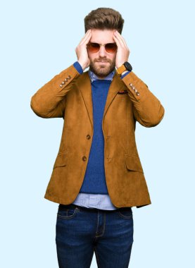 Genç yakışıklı zarif adam giyen güneş gözlüğü çünkü umutsuz ve stresli baş ağrısı acı acı ve migren. Ellerini kafasına.