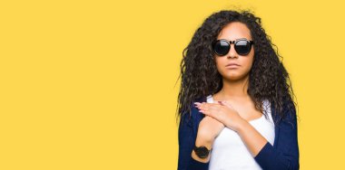 Genç güzel kız ile gülümseyen kıvırcık saçlı giyen moda güneş gözlüğü ile kapalı gözler ve yüzünde minnettar jest ile göğüs üzerinde eller. Sağlık kavramı.