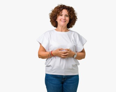 Arka plan eller üzerinde beyaz t-shirt giyen güzel orta ager üst düzey kadın birlikte izole ve rahat ve neşeli gülümseyen parmak çarpı işareti. Başarı ve iyimser