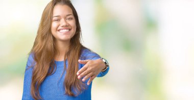 Tebrik ve davet edici dostu sunan karşılıklı gülümseyen izole arka plan üzerinde mavi kazak giyen genç güzel esmer kadın. Başarılı iş.