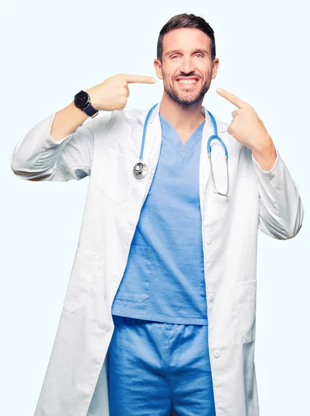 自信を持って示す 指歯と口を指して笑顔分離の背景に医療制服を着てハンサムな医者の男 健康の概念 — ストック写真