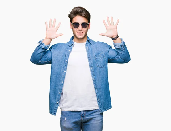 若いハンサムな男でサングラスをかけて分離を示す背景と自信を持って 幸せな笑みを浮かべている間 番号を指で上向き — ストック写真