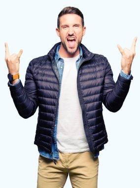 Yakışıklı adam deli ifade rock simge elle yapıyor ile bağırarak kış palto giyiyor. Müzik yıldızı. Ağır kavramı.