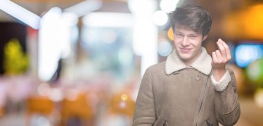 İzole arka plan üzerinde kış ceket giyen genç yakışıklı adam el ve parmaklar emin ifade ile Italyan jest yapıyor