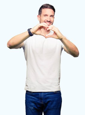 Casual beyaz t-shirt aşık kalp simgesi ve elleriyle şekil gösteren gülümseyen giyen yakışıklı adam. Romantik kavramı.