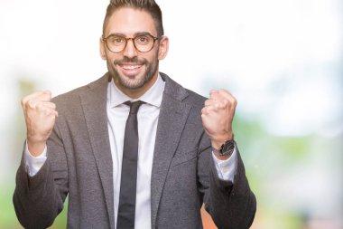 Genç yakışıklı iş adamı izole arka plan kutlama üzerinde şaşırttı ve başarı için kaldırdı kollarını açarak hayret ve gözleri açık. Kazanan kavramı.