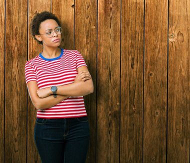 İkna ve kendine güvenen güzel genç Afro-Amerikan kadın gözlük tarafına silahlarla seyir gülümseyen izole arka plan üzerinde çarpı işareti