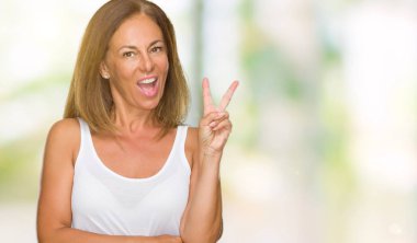 Mutlu yüz zafer işareti yaparken kameraya göz kırpıyor ile gülümseyen izole arka plan güzel orta yaş rahat yetişkin kadın. İki numaralı.