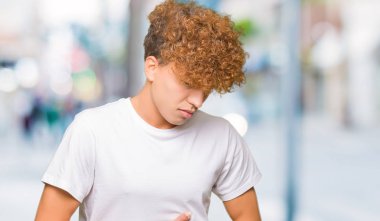 Çünkü mide üzerinde el ile rahat beyaz t-shirt giyen afro saçlı yakışıklı delikanlı mide bulantısı, ağrılı hastalık hasta hissediyor. Ağrısı kavramı.