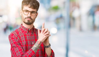 El hareketi ile sembolik silah tutan, çekim silah, kızgın yüz öldürmek oynamaya izole arka plan üzerinde gözlüklü genç yakışıklı adam