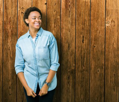 Genç güzel Afrikalı-Amerikalı kadın uzak tarafına yüzünde, doğal ifade gülümseme ile seyir izole arka plan yüzünden. Kendine güvenen gülüyor.