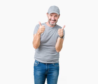 Yakışıklı orta yaş ağarmış komuta sizde Spor şapkası izole arka plan başarı işareti el ile pozitif jest yapıyor üzerinde başparmak gülümseyen ve mutlu. Neşeli bir ifadeyle, kazanan jest kameraya bakıyor.