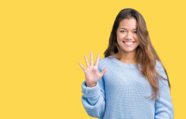 Üzerinde gösterilen ve parmakları ile işaret izole arka plan mavi kış kazak giyen genç güzel esmer kadın kendinden emin ve mutlu gülümseyerek süre beş numara.