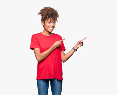 Güzel genç Afro-Amerikan kadın gülümseyerek ve iki elleri ve parmakları ile tarafına işaret kamera bakarak izole arka plan üzerinde.