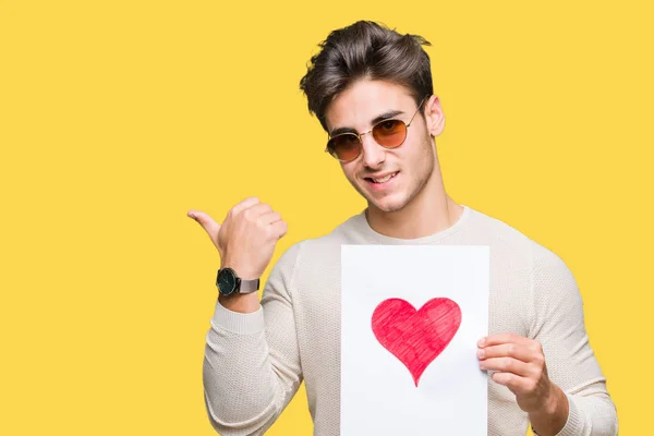 Joven Hombre Guapo Sosteniendo Tarjeta Con Corazón Rojo Sobre Fondo — Foto de Stock