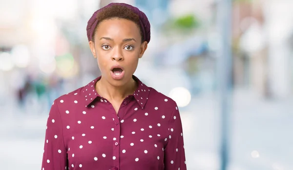 Beautiful young african american woman wearing head scarf over isolated background afraid and shocked with surprise expression, fear and excited face.