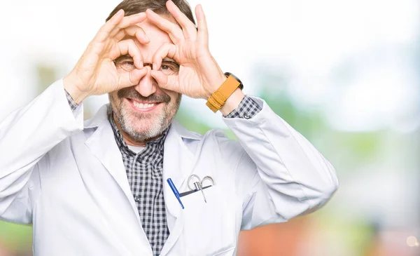 医療用コートを着た中年の医者男性は 舌を突き出し 指を通して目を見るようなOkジェスチャーをしています クレイジー表現 — ストック写真