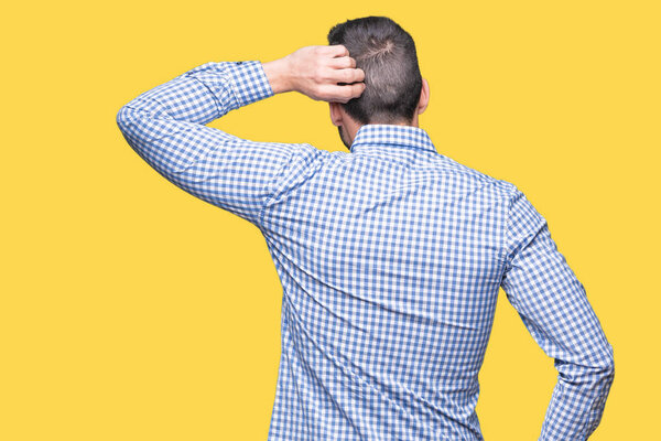 Молодой красивый мужчина на изолированном заднем плане думает о сомнениях с рукой на голове
