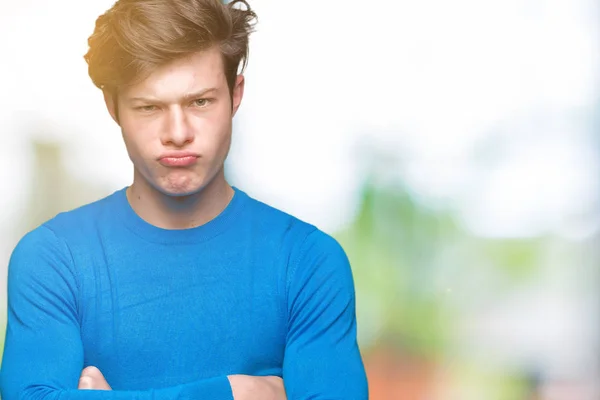 年轻的帅哥穿着蓝色毛衣 在孤立的背景怀疑和紧张 不赞成表情在脸上交叉的手臂 消极的人 — 图库照片