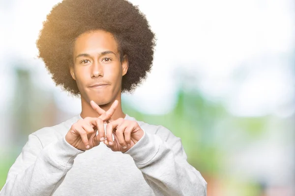 スポーティなスウェット シャツ拒絶反応式交差指負の符号をやって身に着けているアフロの髪の若いアフリカ系アメリカ人 — ストック写真