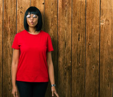 İzole arka plan yapma balık yüzüne dudaklı, çılgın ve komik bir jest gözlüklü güzel genç Afro-Amerikan kadın. Komik ifade.