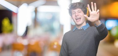 İzole arka plan üzerinde genç yakışıklı zarif adam gösteren ve parmak sayısı dört ile işaret kadar güven ve mutlu gülümseyen.