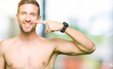 Gömleksiz yakışıklı çıplak göğüs gösterilen işaretçi el ile parmak yüz ve burun, neşeli gülümseyen