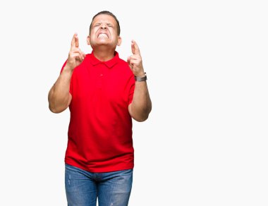 Orta yaş geçiş parmakları umut ve gözleri kapalı ile gülümseyen izole arka plan Arap adam. Şans ve batıl kavramı.