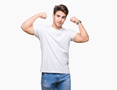 Kol kasları gururlu gülümseyen gösterilen izole arka plan üzerinde beyaz t-shirt giyen genç yakışıklı adam. Fitness kavramı.