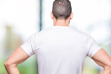 Açık havada arka planda beyaz t-shirt giyen yakışıklı adam geriye vücut üzerinde kollar ile bakıyor ayakta