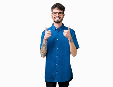 Yakışıklı delikanlı izole arka plan başarı işareti el ile pozitif jest yapıyor üzerinde gözlük takan başparmak gülümseyen ve mutlu. Neşeli bir ifadeyle, kazanan jest kameraya bakıyor.