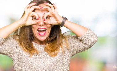 Dilini, parmaklarının arasından baktığını yapışmasını dürbün gibi ok jest yapmak moda kazak giyen güzel orta yaş kadın. Deli ifade.