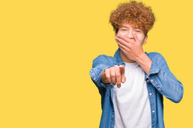 Afro saçlı kot giyen genç yakışıklı adam ceket sizin parmak el kamerasıyla ağzına, utanç ifadesi işaret eden gülme