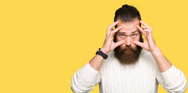 Parmaklarıyla, uykulu ve sabah yorgunluk için yorgun gözlerini açmaya çalışırken kış kazak giyen genç hipster adam